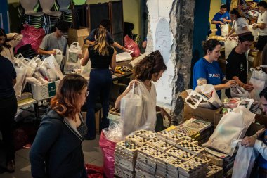 Tel Aviv, İsrail, 5 Mart 2026 genç İsrailli gönüllüler yerel bir dağıtım merkezinde insani yardım kutuları oluşturup paketlediler. Çocuklar için gıda ve eşyalar da dahil olmak üzere erzaklar, yerlerinden edilen siviller ve mülteciler için hazırlanmaktadır.