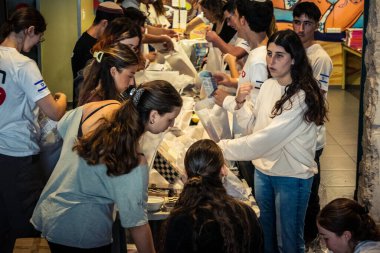 Tel Aviv, İsrail, 5 Mart 2026 genç İsrailli gönüllüler yerel bir dağıtım merkezinde insani yardım kutuları oluşturup paketlediler. Çocuklar için gıda ve eşyalar da dahil olmak üzere erzaklar, yerlerinden edilen siviller ve mülteciler için hazırlanmaktadır.