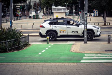 Tel Aviv, İsrail, 7 Mart 2026 Tel Aviv şehir trafiğinde ilerleyen profesyonel bir beyaz taksi aracı..