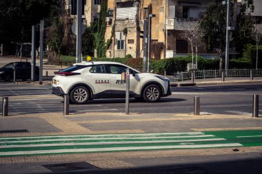 Tel Aviv, İsrail, 7 Mart 2026 Tel Aviv şehir trafiğinde ilerleyen profesyonel bir beyaz taksi aracı..
