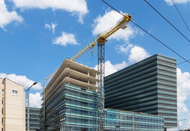 Gökyüzünün arka planına ve tamamlanmamış binalara karşı inşaat vinci.