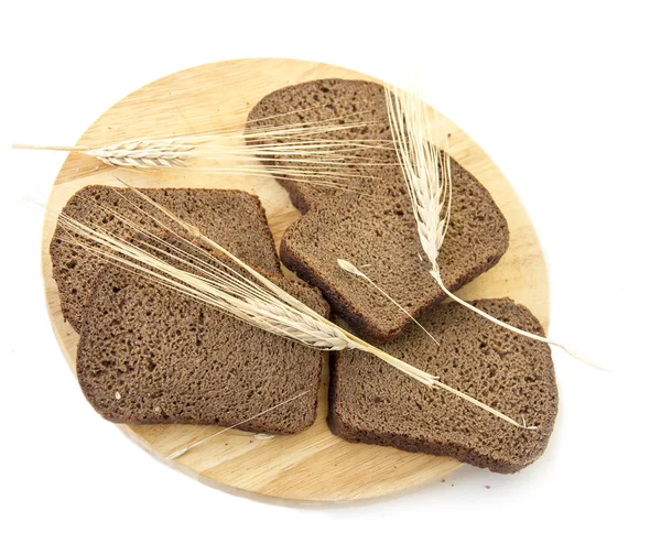 Slices of rye bread on a wooden board and ears of rye — Stock Photo, Image