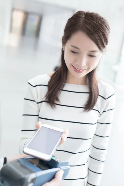 Mujer joven que paga por teléfono inteligente — Foto de Stock