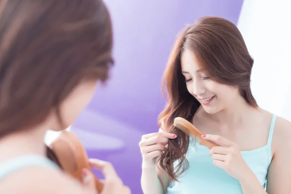 Jovem mulher está penteando o cabelo — Fotografia de Stock