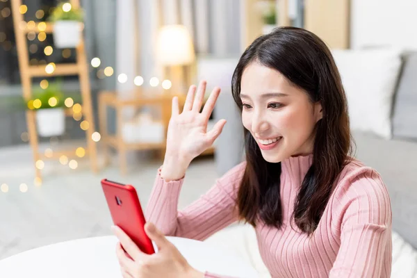 아시아인젊은 여자는 거실에서 친구와 스마트폰으로 비디오 채팅을 행복하게 지낸다 — 스톡 사진