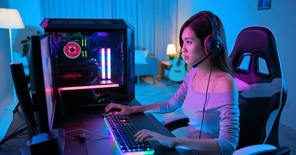 Young Asian Pro Gamer Girl Playing in Online Video Game with rgb keyboard and mouse at home