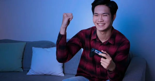 アジア人男性はゲームパッドを使用して家で夕方にビデオゲームに勝つ — ストック写真