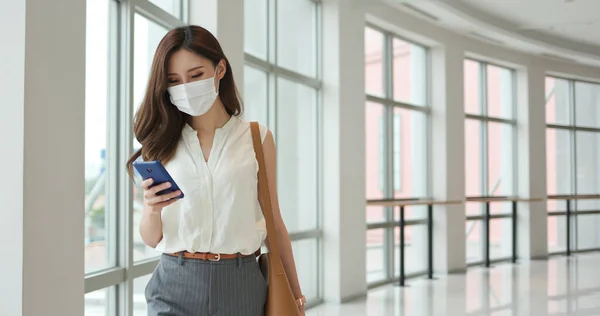 close up of asian young businesswoman wearing surgical mask face protection is using smart phone  on her business trip