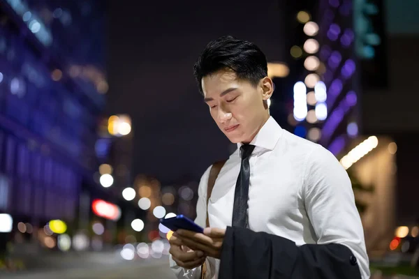 若いアジアのビジネスマンは携帯電話を持っていて街の路上でタクシーを待っています — ストック写真
