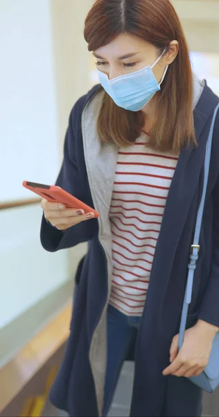 Asiatisk Kvinne Bruker Smarttelefon Når Hun Står Rulletrapp Med Kirurgisk – stockfoto