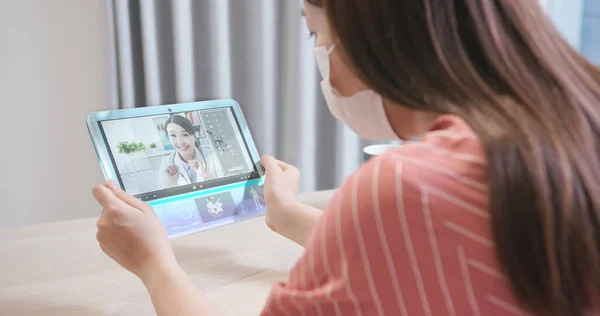 远程医疗的概念 在不久的将来 亚洲女病人的后视镜会在家中用透明的平板电脑向医生咨询她的健康状况 — 图库照片
