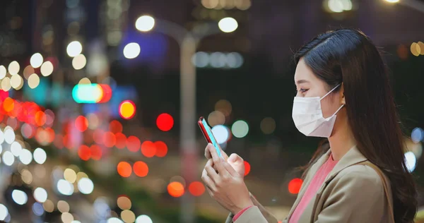 フェイスマスクをしたアジア人女性は街中で交通事情の悪い通勤中にスマートフォンの屋外を利用しています — ストック写真
