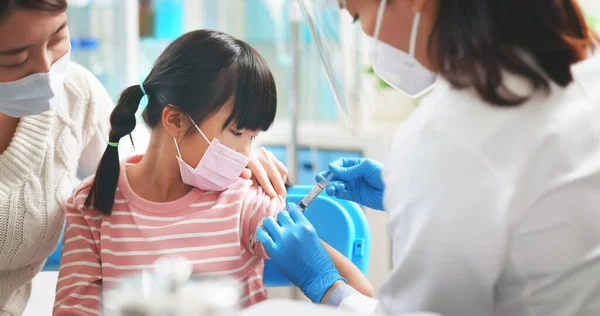 亚洲女医生戴着手套和隔离面具 在医院与母亲在一起的患儿肩部接种了Covid 19疫苗 — 图库照片