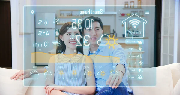许多聪明的家庭观念 亚洲夫妇在客厅的沙发上看天气的虚拟屏幕 — 图库照片