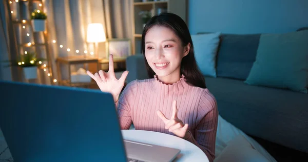 Sign language - Hearing impaired girl wearing winter cloth is making a love sign to her friend on video call online by laptop at home