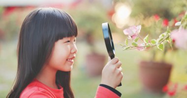 Asian girl hold magnifer and observe flower with curiosity happily clipart