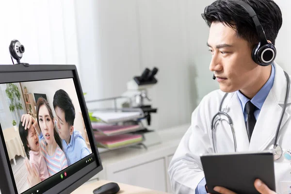 远程医疗的概念 亚洲男性儿科医生正在通过网络摄像头和数码平板电脑记录家人的心声 — 图库照片