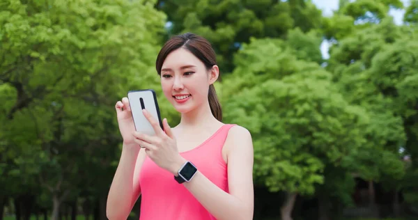 スポーツアジアの女性は公園内でスマートフォンを使い — ストック写真