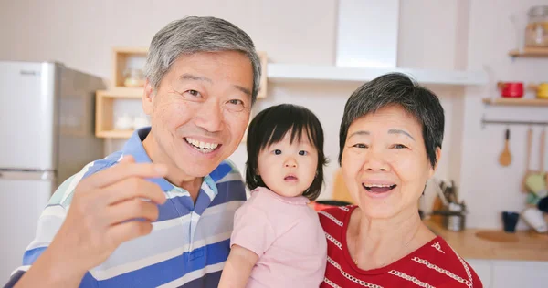 亚洲的一对老年夫妇和他们的孙女在家里愉快地通过摄像头进行视频聊天 — 图库照片