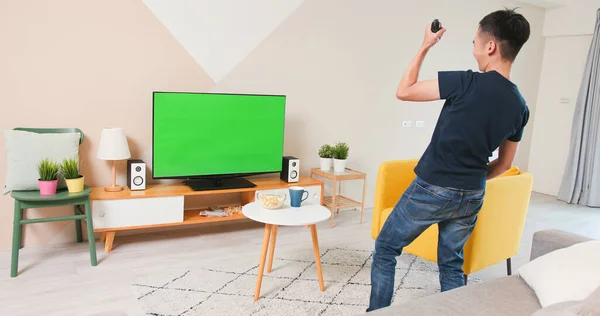 亚洲年轻人在一个绿色的彩色关键电视屏幕上玩并赢得了动感游戏 然后在家里摇着胳膊 — 图库照片