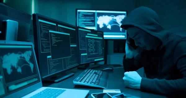 亚洲男性黑客的侧面形象是用电脑和电话交谈 他觉得很严肃 很生气 — 图库照片