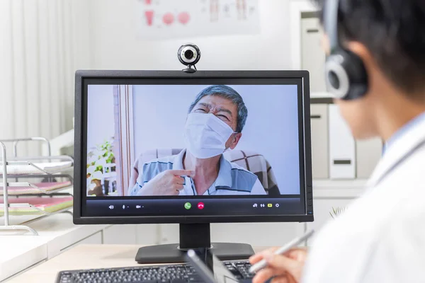 远程医疗的概念 亚洲年轻医生的后视镜是在网上聆听老年病人的声音 — 图库照片