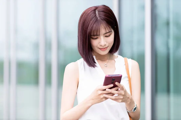 Asyalı Genç Kadını Şehirde Işe Giderken Akıllı Telefon Kullanıyor — Stok fotoğraf