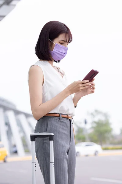Asiatisk Ung Forretningskvinne Bærer Ansiktsmaske Bruker Smarttelefon Med Koffert Forretningsreisen – stockfoto