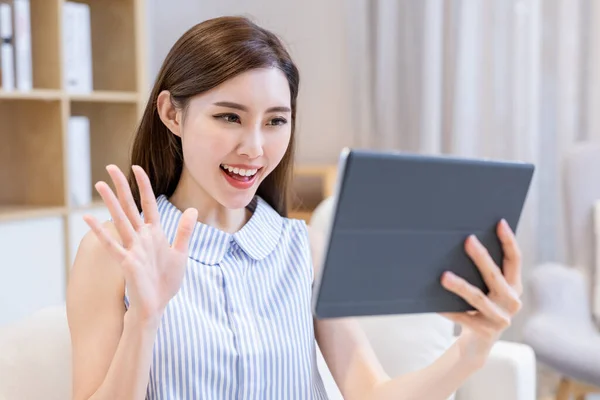 아시아인젊은 여자는 거실에서 디지털 태블릿으로 친구들 비디오 채팅을 스톡 사진
