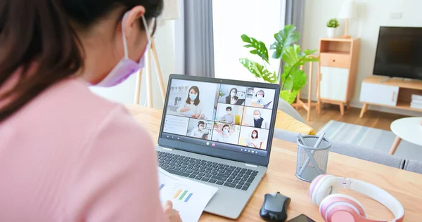 远程工作的概念 带着面具的亚洲女商人的后视镜使用笔记本电脑参加在家里客厅里举行的集体视频会议 — 图库照片