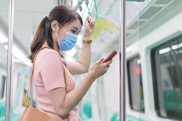 Asiatisk Forretningskvinne Bruker Smarttelefon Med Kirurgisk Maskebeskyttelse Mens Hun Pendler – stockfoto