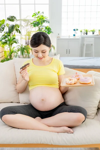 Концепция Нездорового Питания Азиатская Улыбающаяся Беременная Женщина Пончиками Гостиной — стоковое фото