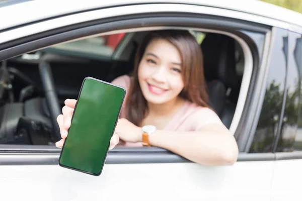 Asian Woman Shows Green Screen Mobile Phone While Driving Car – stockfoto