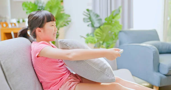 亚洲女孩坐在沙发上 一边看电视一边笑着 — 图库照片