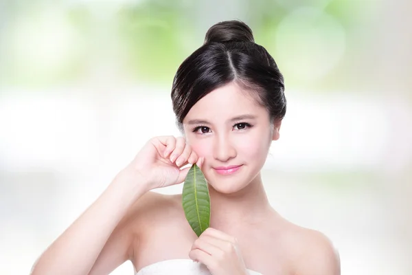 Vacker kvinna ansikte stående med grönt blad — Stockfoto