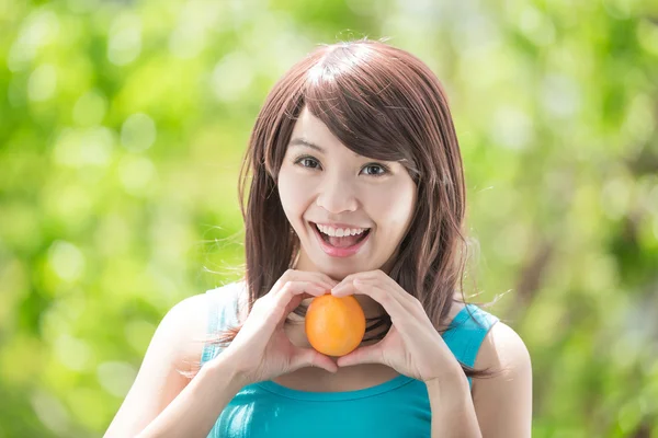 Mujer joven sosteniendo naranja — Foto de Stock