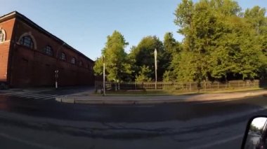 Yol kenarında ağaçlar olan ıssız bir şehir yolunun manzarası. Sabah güneşi ağaçların arasından yükseliyor.