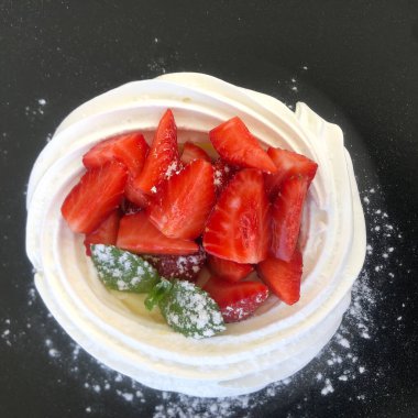 Koyu arkaplanda taze çilekli kremalı pasta.