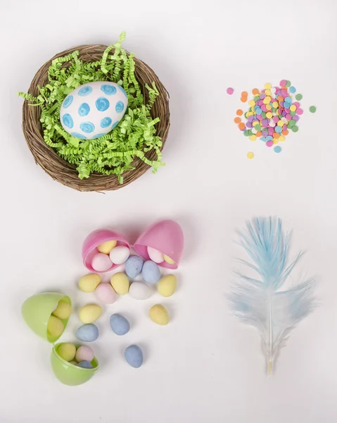 Œufs de Pâques, panier et bonbons sur fond blanc — Photo