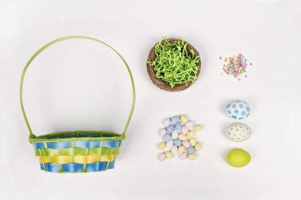 Œufs de Pâques, panier et bonbons sur fond blanc — Photo