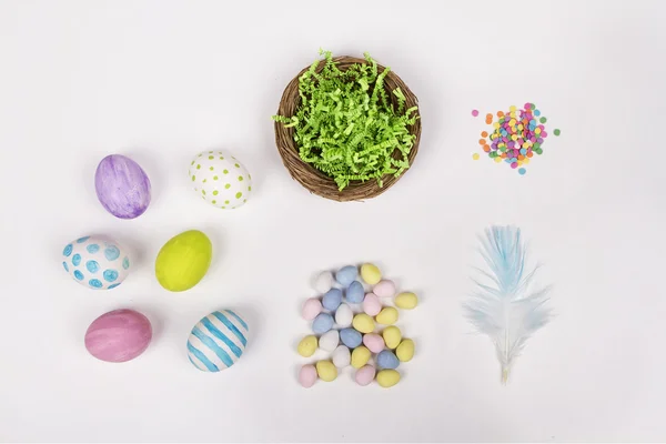 Ovos de Páscoa, cesta e doces em um fundo branco — Fotografia de Stock