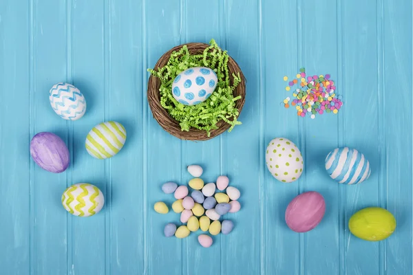 Ovos de Páscoa, cesta e doces em um fundo azul — Fotografia de Stock