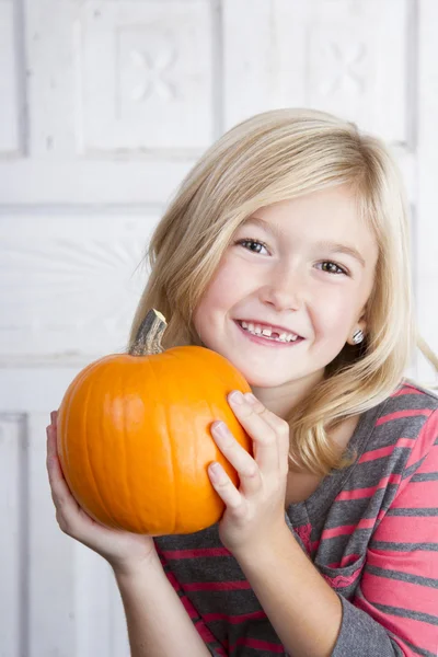 Kind hält kleinen Kürbis am Gesicht hoch — Stockfoto