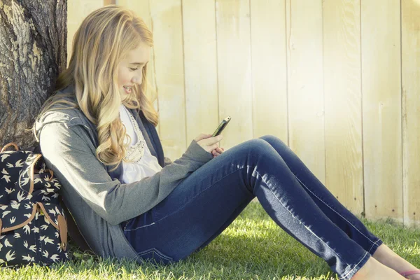 Teenage girl smiling while using a cell phone — Stock Photo, Image