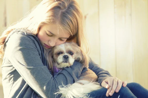 A sad or depressed teenage girl hugging a small dog — Stock Photo, Image