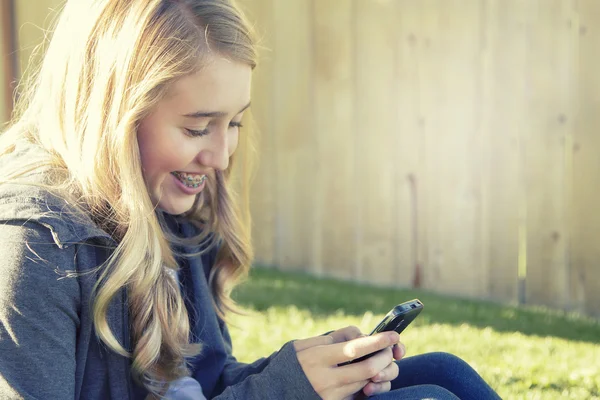 携帯電話を使用しながら笑っている 10 代の女の子 — ストック写真