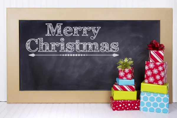 Boże Narodzenie prezenty zgrupowane wokół tablicy szkolnej — Zdjęcie stockowe