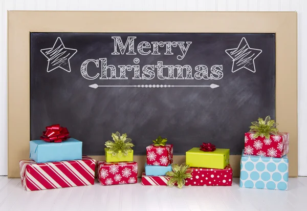 Christmas presents grouped around a chalkboard — Stock Photo, Image