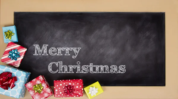 Christmas presents grouped around a chalkboard — Stock Photo, Image