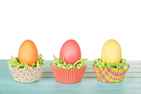 Ovos de Páscoa tingidos em um ninho de confete de grama verde e bolo de xícara — Fotografia de Stock